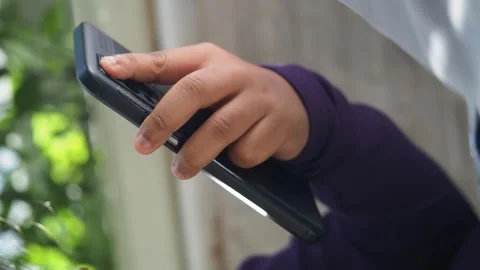 Close up of child hands holding smartphone and using finger to tap screen. Stock Footage 332109036