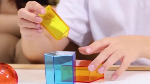 Close Up of Child Hands Stacking Translucent Colorful Geometric Blocks Stock Footage 327425966