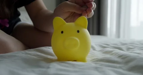 Close-up child hand's throwing coins into piggy bank. Children in financial Stock Footage 286249054