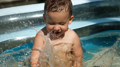 Close-up of a child having fun swimming in an outdoor pool. Video stock 128181867