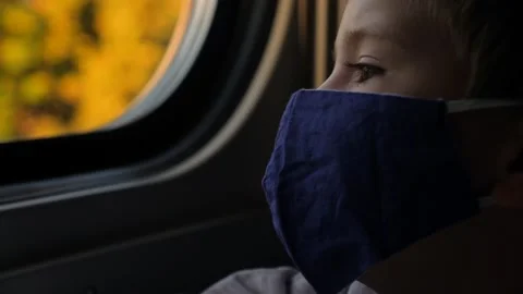Close up child mask face boy looking out window train passenger kid thinking Stock Footage 164881837