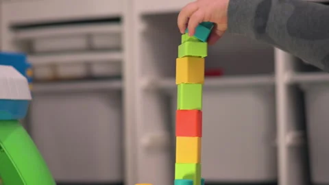 Close Up Child Placing Building Block on Tower That Falls Stock Footage 330970536