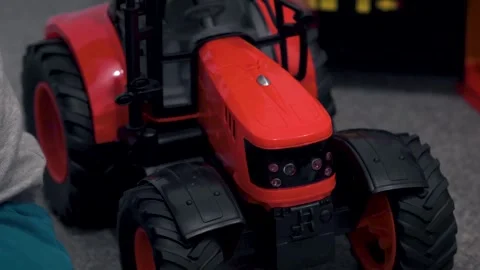 Close-Up of Child Playing with Red Toy Tractor Stock Footage 325741879