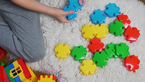 Close-up the child plays with colored puzzle blocks, the kid collects figure fro Stock Footage 118434645