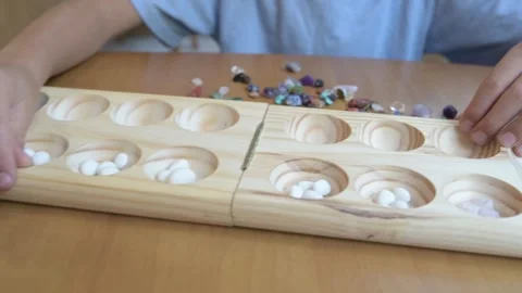 Close-up of child s hands playing mancala Kalah board game with stones Stock Footage 316095802