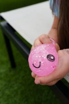 Close-up of a child squeezing a pink glitter squishy toy with smiling face Stock Photos
