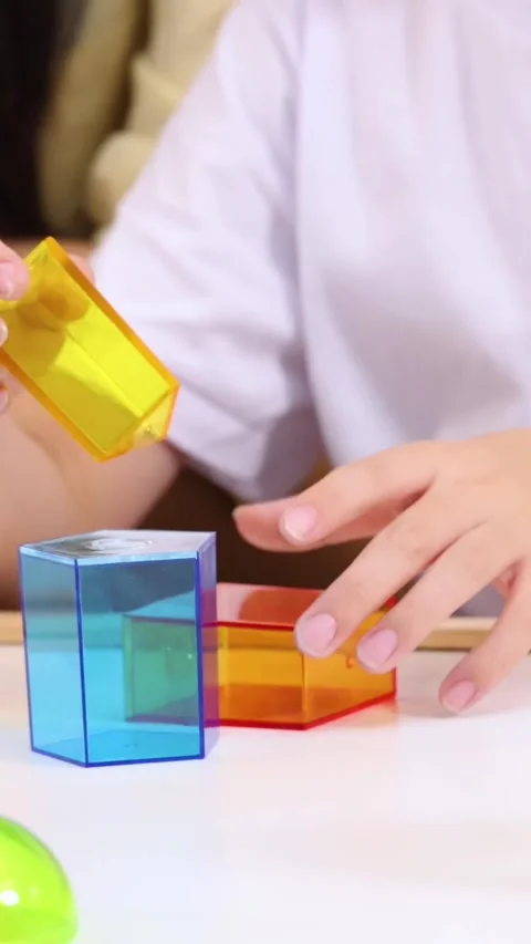 Close Up of Child Stacking Translucent Geometric Blocks in Vertical Format Stock Footage 327944744