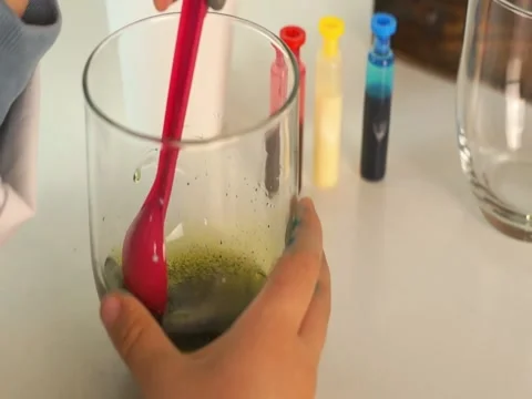 Close-up of Child Stirring Green Solution for Chemistry Project Stock Footage 331261666