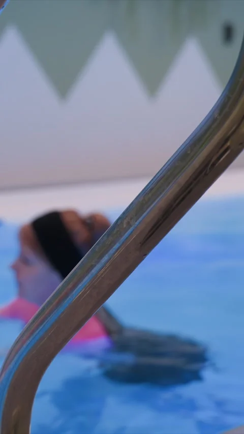 Close up child swimming in indoor pool near metal handrail with chevron Stock Footage 342785867