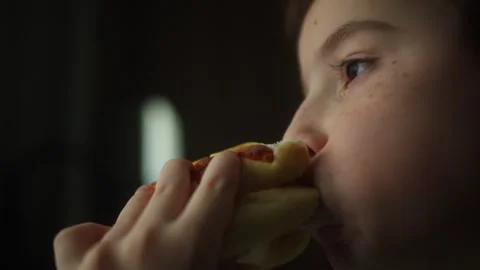 Close up of a child taking a bite of a homemade burger with fresh lettuce and a Stockbeeldmateriaal 340746069