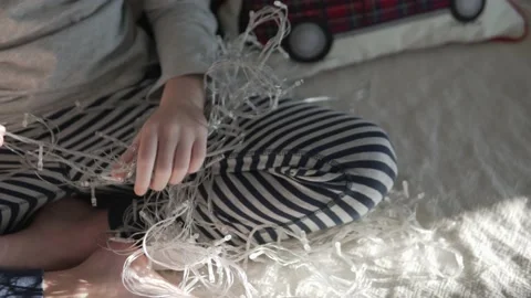 Close-up, the child untangles the New Year's garland with glowing light bulbs at Stock Footage 144658871