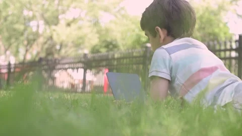 Close up Child using Digital Tablet sitting on the grass outdoors Stock Footage 204092979