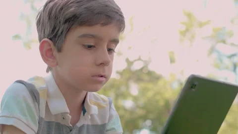 Close up Child using Digital Tablet sitting on the grass outdoors Stock Footage 204113431