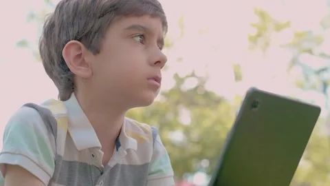 Close up Child using Digital Tablet sitting on the grass outdoors Stock Footage 204113438