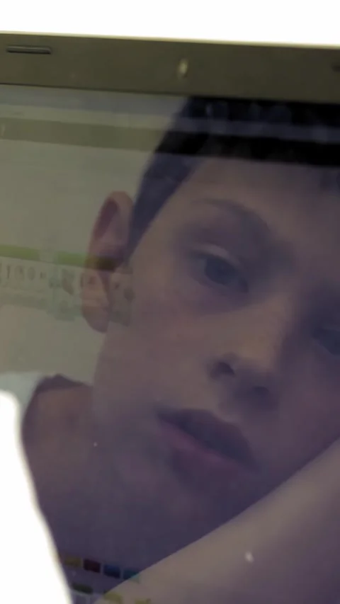 Close-up, a child working on a laptop. the face of the child is reflected in the Video stock 315449304
