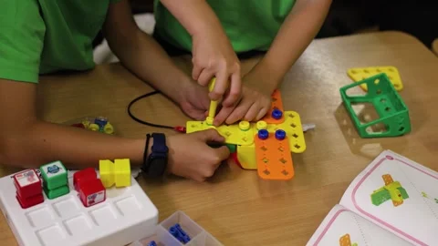Close up of children assembling colorful plastic construction pieces with Stock Footage 318212185
