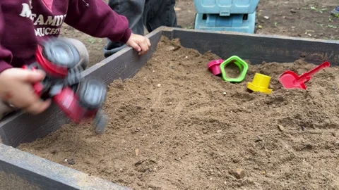Close-up of children playing together in a sandbox with toy trucks, excavator Stock Footage 346691189
