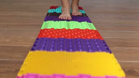 Close-up of children's feet stepping on multi-colored orthopedic mats with Vidéo 169701213