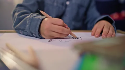 Close-up of children's hands of a boy drawing with a pencil on a letter Video stock 283831273