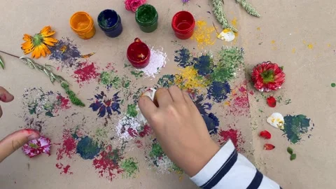 Close-up of children's hands that create a drawing using a flower by poking. Stock Footage 202606686