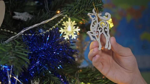 Close-up of children's hands decorating a Christmas tree with a deer toy against Stock Footage 166966254