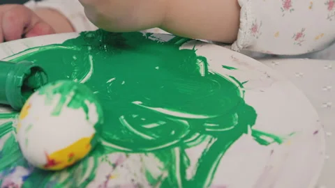 Close-up of children's hands drawing green paints on a plate and an egg Stock Footage 219787897