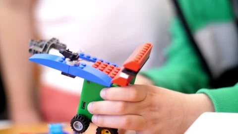 Close-up, children's hands hold a multicolored small car assembled from a Video stock 89227044
