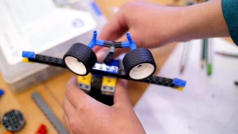 Close-up, children's hands hold a multicolored small robot, machine, assembled Video stock 89228396