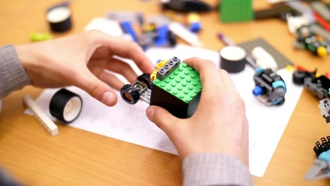 Close-up, children's hands hold a multicolored small robot, machine, assembled Stock Footage 89242893