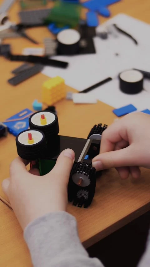 Close-up, children's hands hold a multicolored small robot, machine, assembled Video stock 316780970