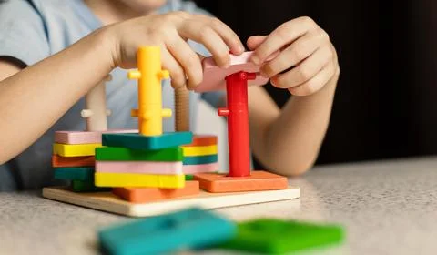 Close-up of children's hands playing with an educational multi-colored puzzle Stock Photos