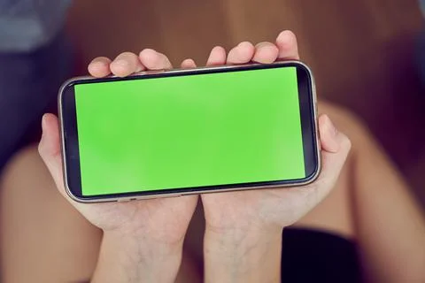 Close-up of children's hands using a phone with a green screen. A little girl is Stock Photos