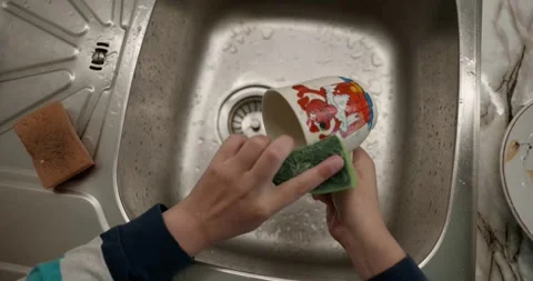 Close-up children's hands wash kitchen utensils sink and dishes. 4K  Stock Footage 345448212