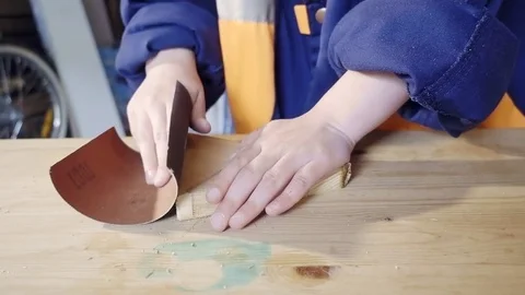 Close-up of children's hands to work with wood detail. Sanding the edges with Video stock 76317436