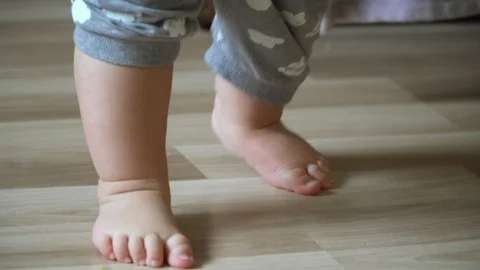 Close-up of children's legs taking their first steps and falling down Stock Footage 107767194
