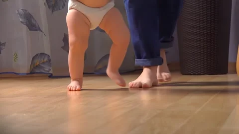 Close-up of childrens legs taking their first steps next to their mother Video stock 290516913