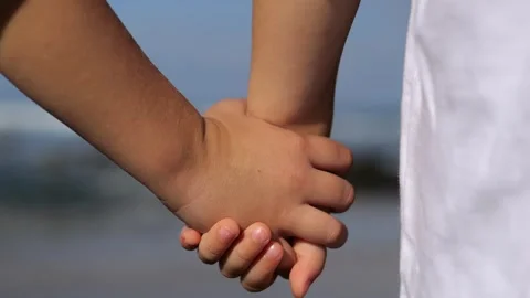 Close up of children's tightly holding hands. Children hold hands on seashore Stock Footage 240551130