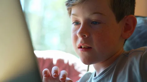 Close up of child’s face  doing schoolwork at home on laptop Stock Footage 129973958
