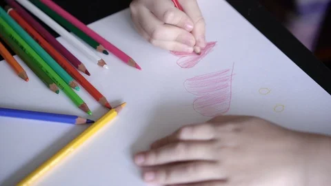 Close-up of a child's hand drawing a red pencil a heart on a homemade postcard Stock Footage 102054309