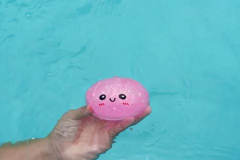 Close-up of a child’s hand holding a dumpling squishy in the pool water Foto stock
