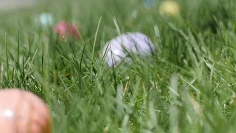 Close-Up Of Child's Hand Picking Up An Orange Easter Egg Video stock 77522435