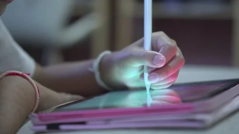 Close-up of a child's hand using a stylus pen drawing on a digital tablet Stockbeeldmateriaal 333078933