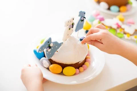 Close-up of child's hands decorating Easter cake with festive decor, sugar ra Stock Photos