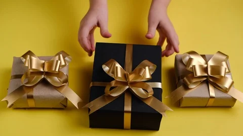 Close up of child's hands gives gift boxes on pastel yellow background. Stock Footage 120744580