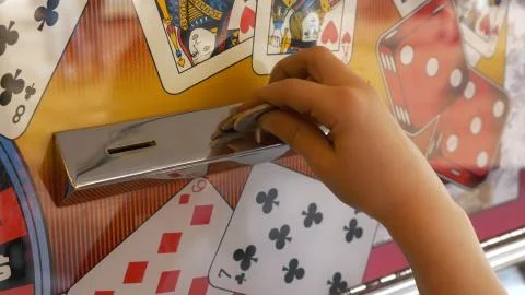 Close-up Of Childs Hands Inserting Coin Into Slots Machine Photos