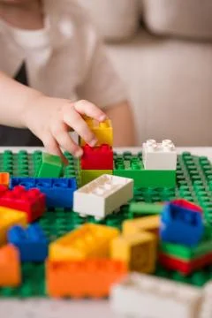 Close up of child's hands playing with colorful plastic bricks at the table.  Stock Photos