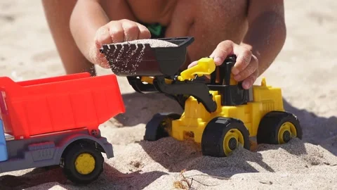 Close-up of a child's hands playing in the sand with plastic cars on a sandy Stock Footage 138993543