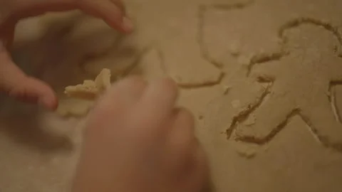 Close-up of child's hands removing dough around carved gingerbread 库存影片 336374737