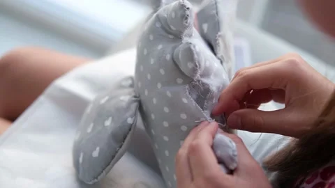 Close-up of a child's hands sewing a soft toy. Stock Footage 217960758