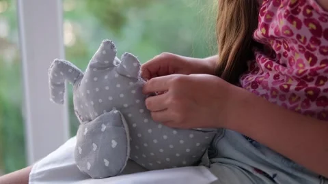 Close-up of a child's hands sewing a soft toy. Video stock 243259843